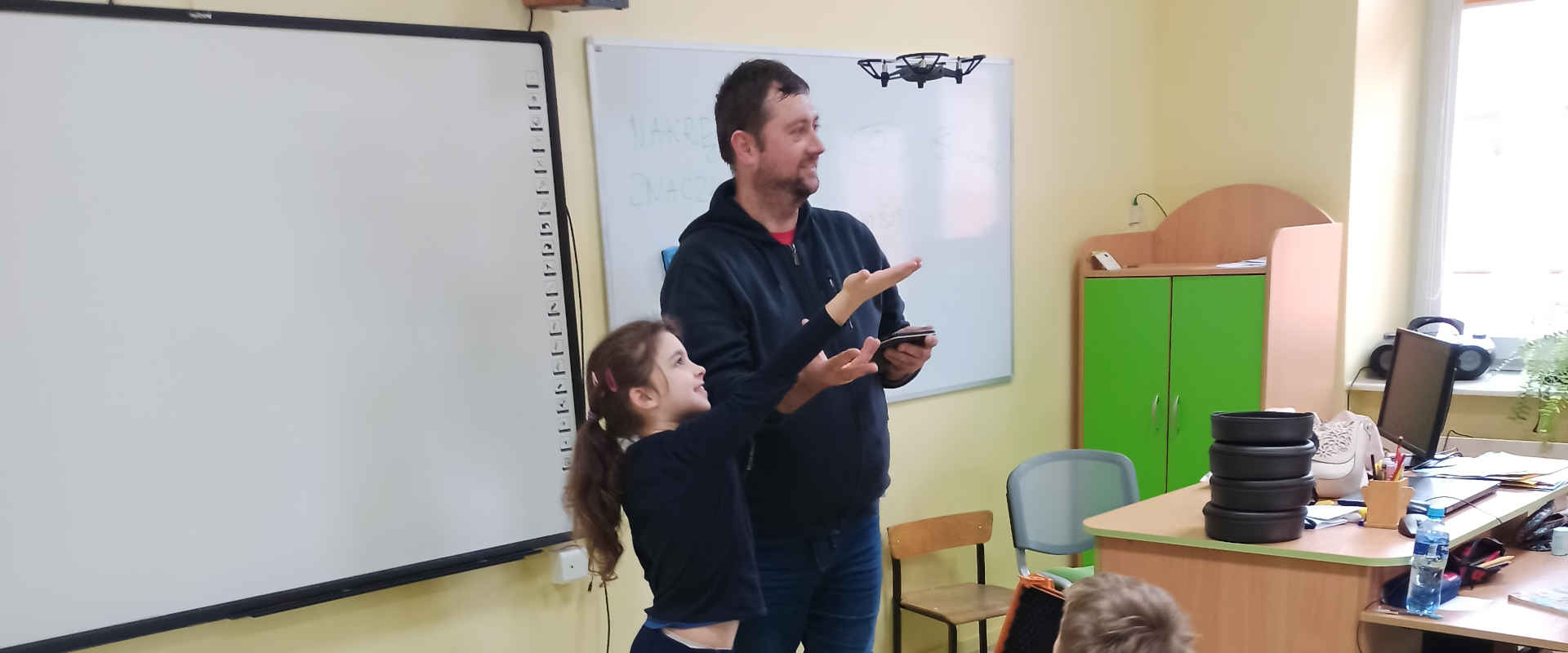 Nauczyciel z uczennicą testują latającego drona
